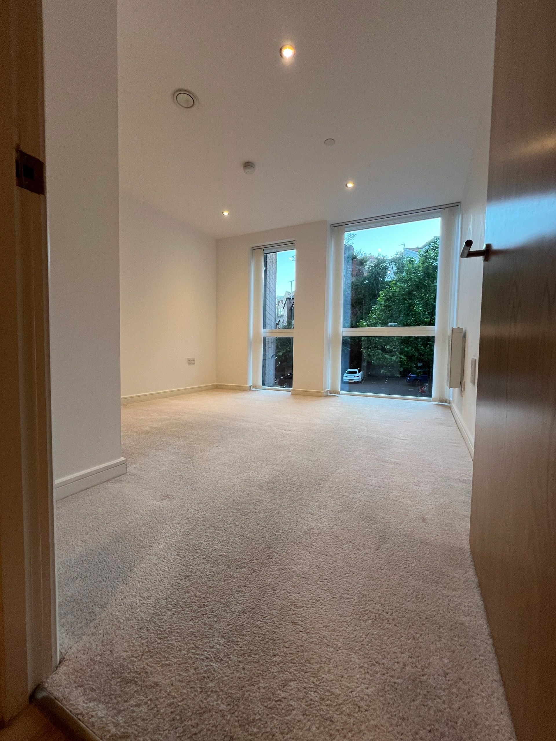 Clean empty room with pale carpet and patio doors